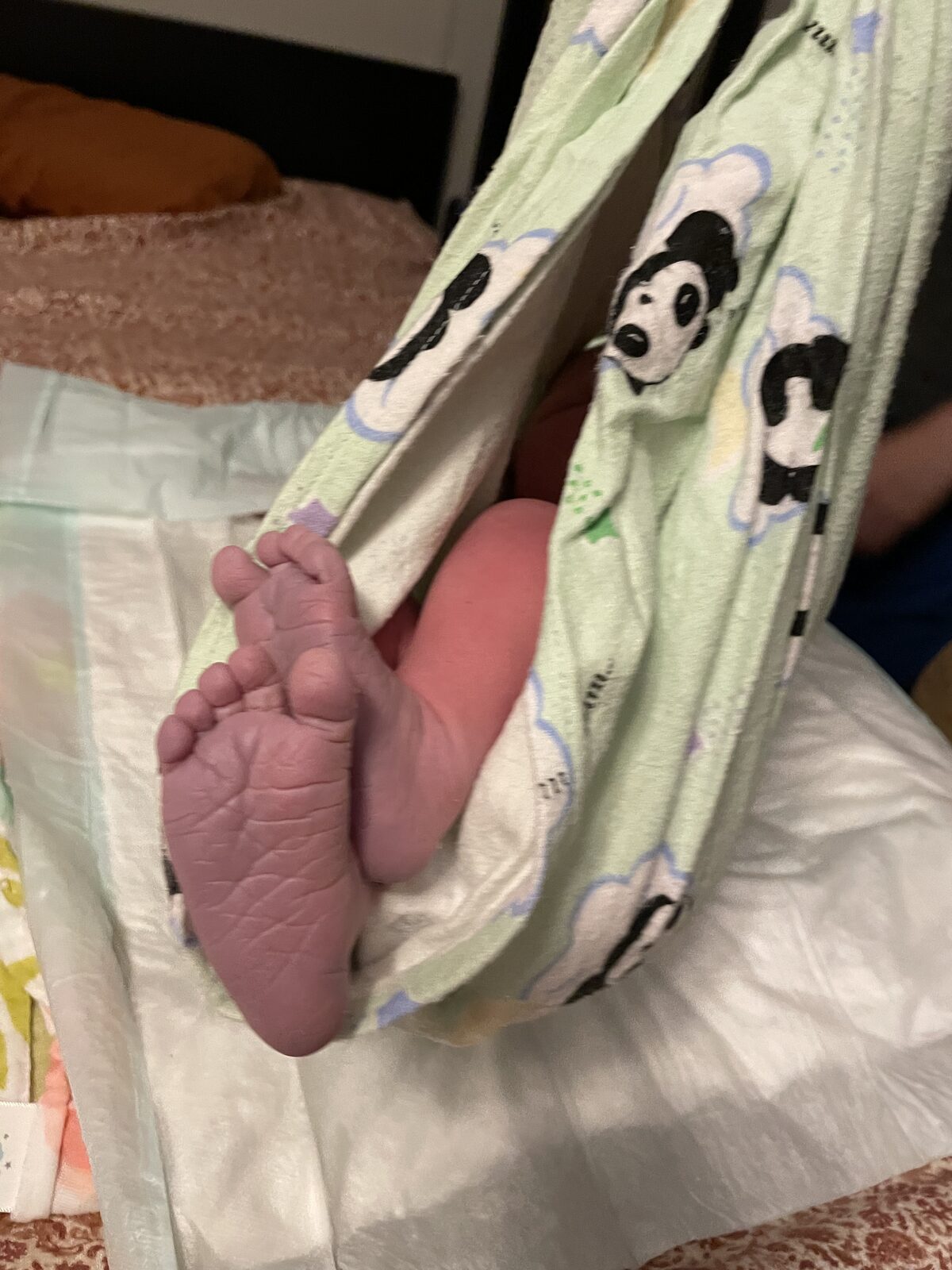 Newborn feet in a soft panda sling