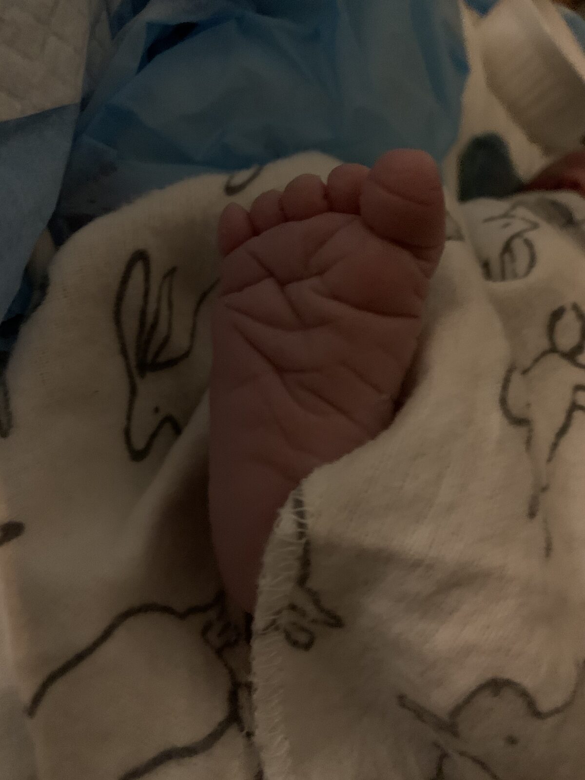 A newborn's foot resting on a soft blanket