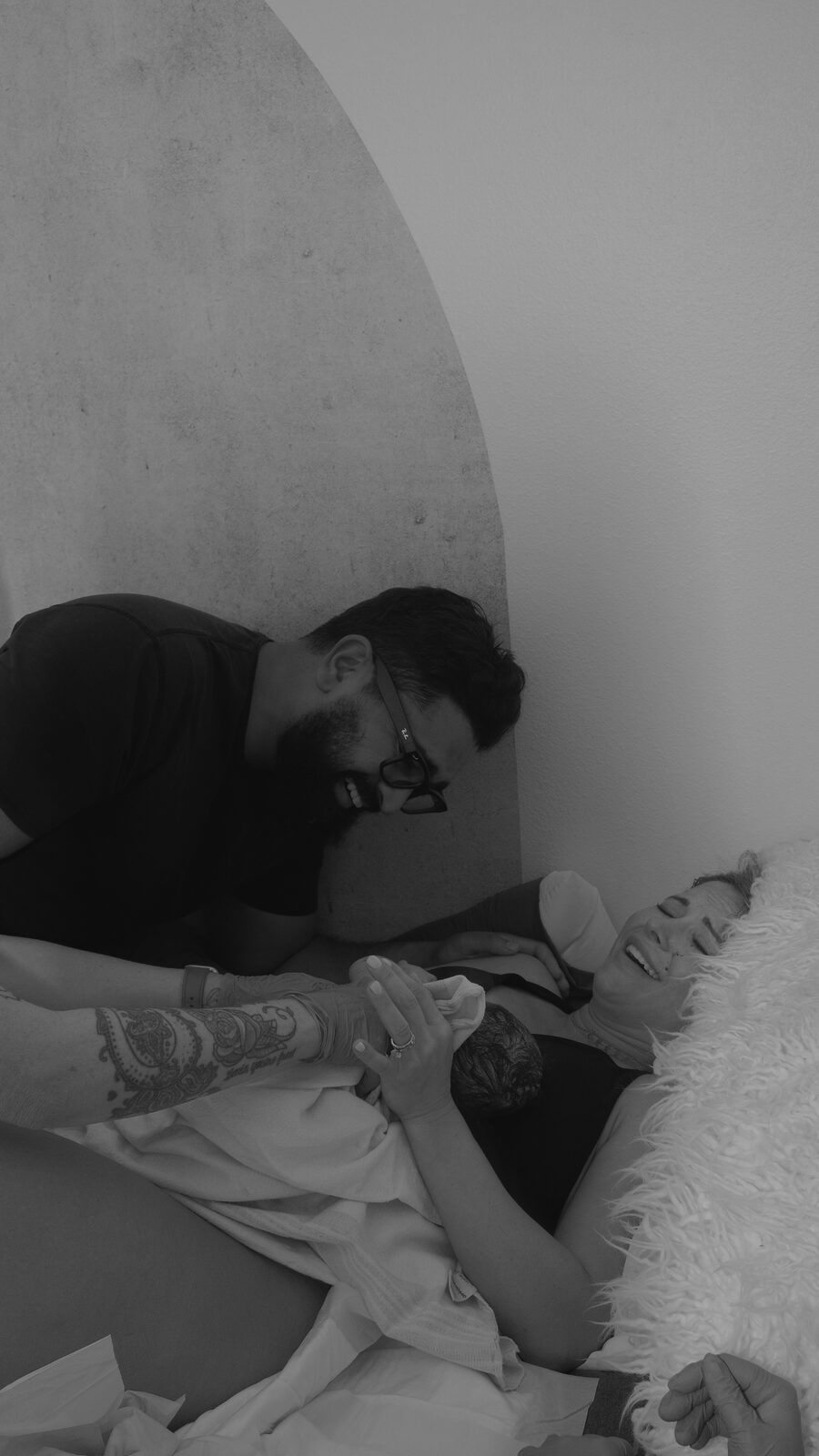 New parents laughing together with their just-born baby